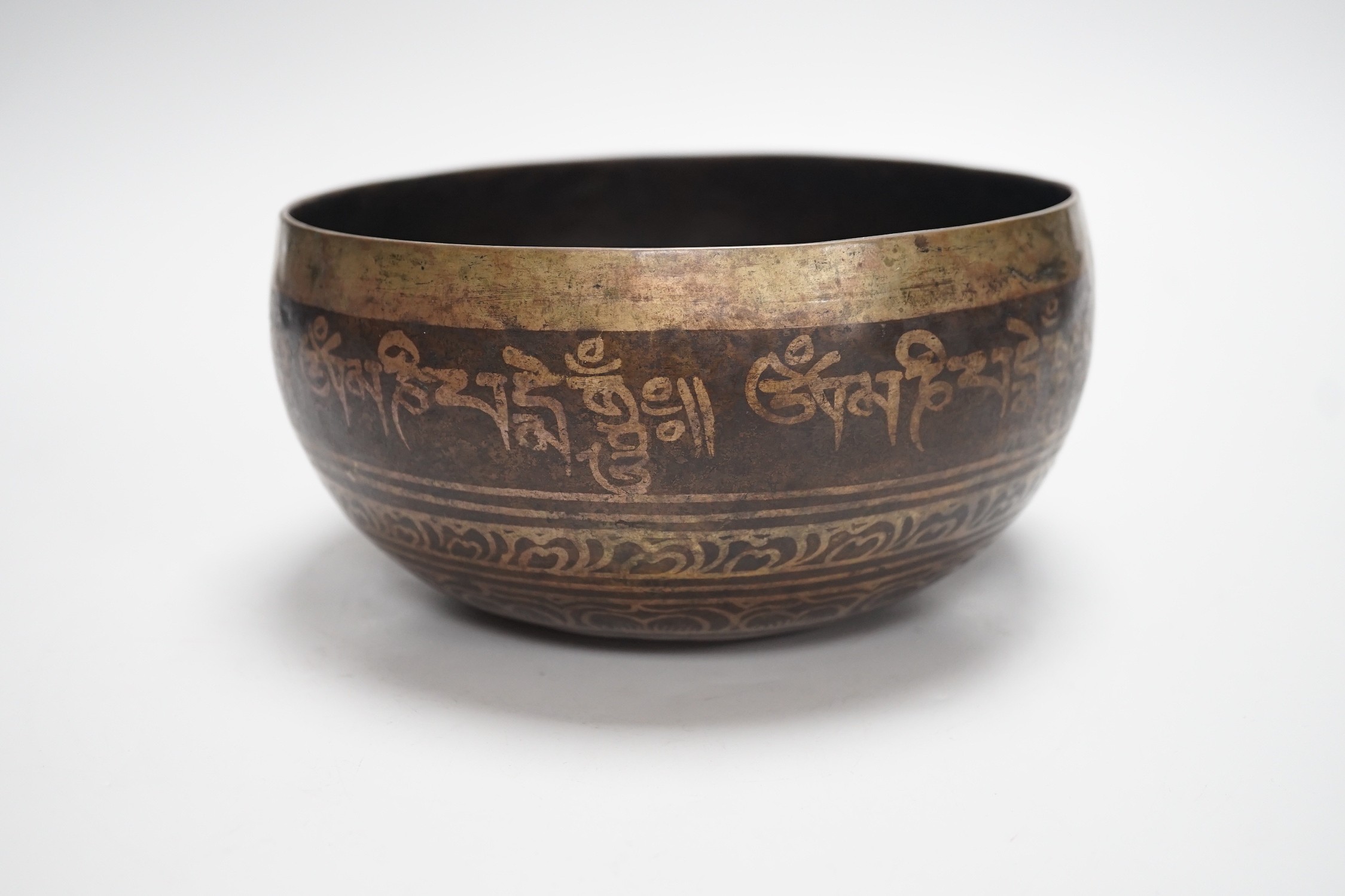 A bronze Nepalese temple bowl decorated with script, 18cm diameter